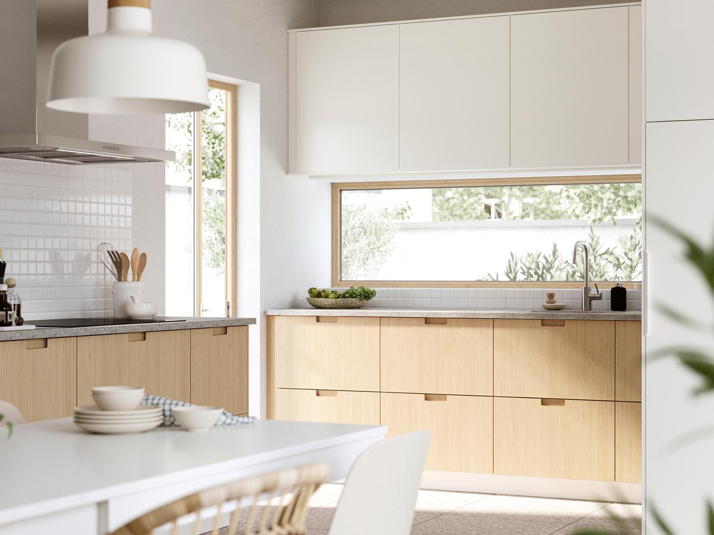 A sun-drenched kitchen in modern style. The bottom cabinets have FRÖJERED fronts and the top cabinets have VEDDINGE fronts.
