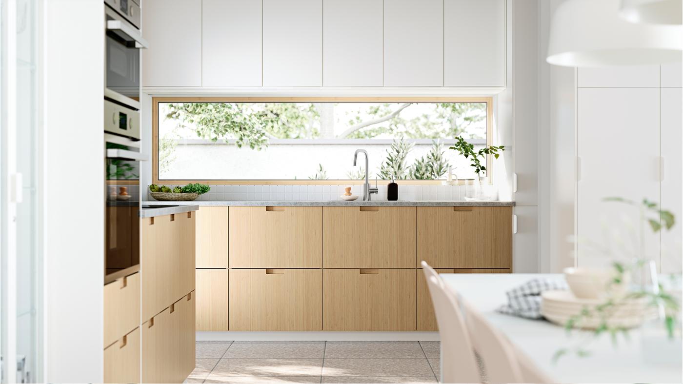 A sun-drenched kitchen with windows facing the garden. FRÖJERED kitchen fronts, in bamboo, are combined with fronts in white.