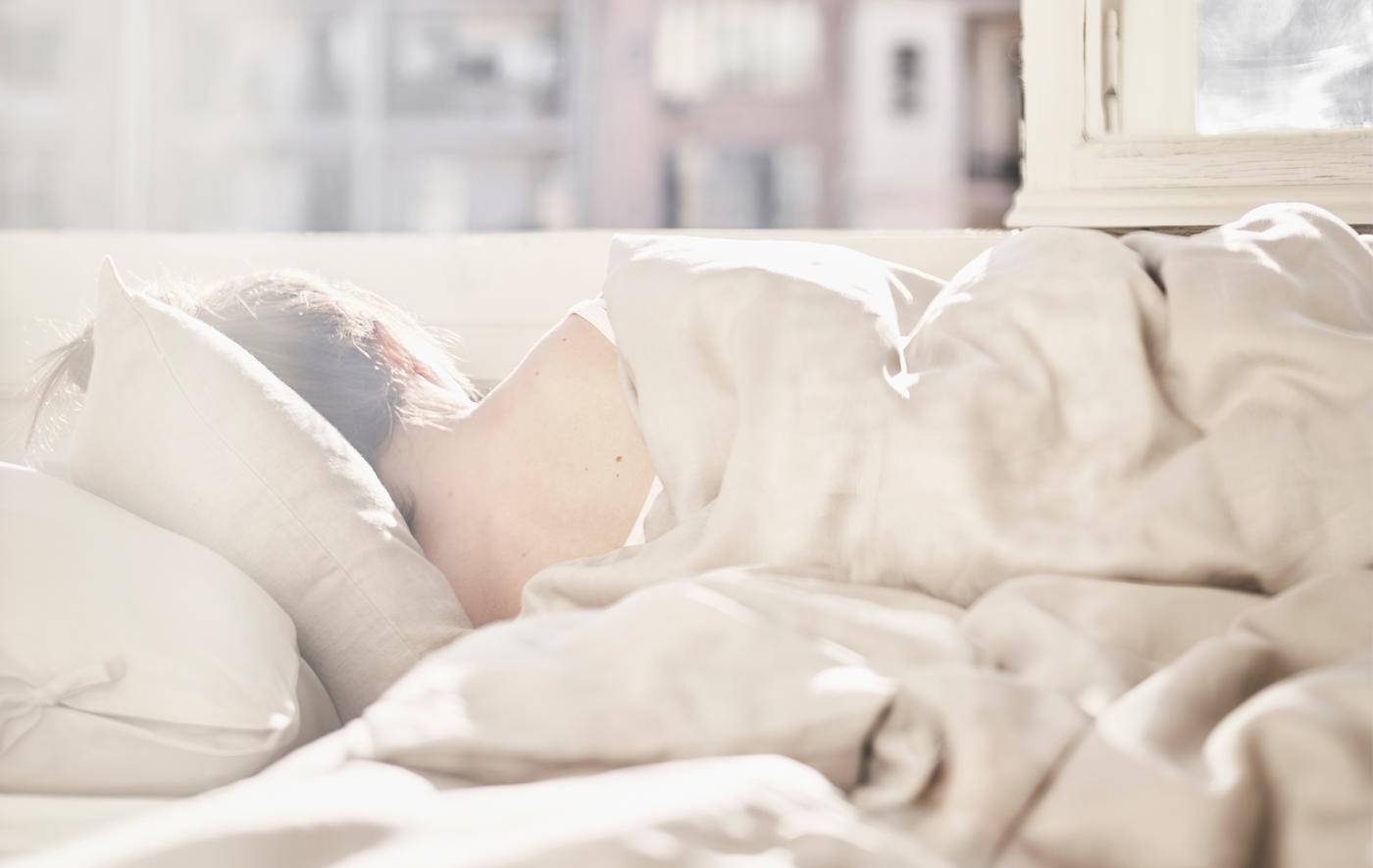 A sunlit bedroom with sleeping woman.