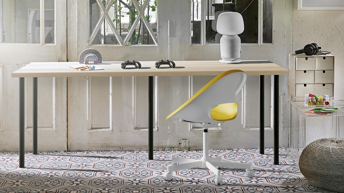 A sunlit room with a long, five-legged desk combined by an oak-effect LAGKAPTEN tabletop and black ADILS legs.