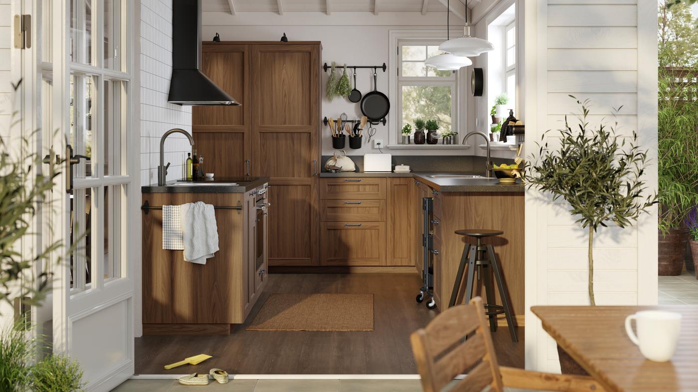 A sunny, white traditional-style kitchen with ENKÖPING brown walnut effect fronts and black mineral effect worktops.