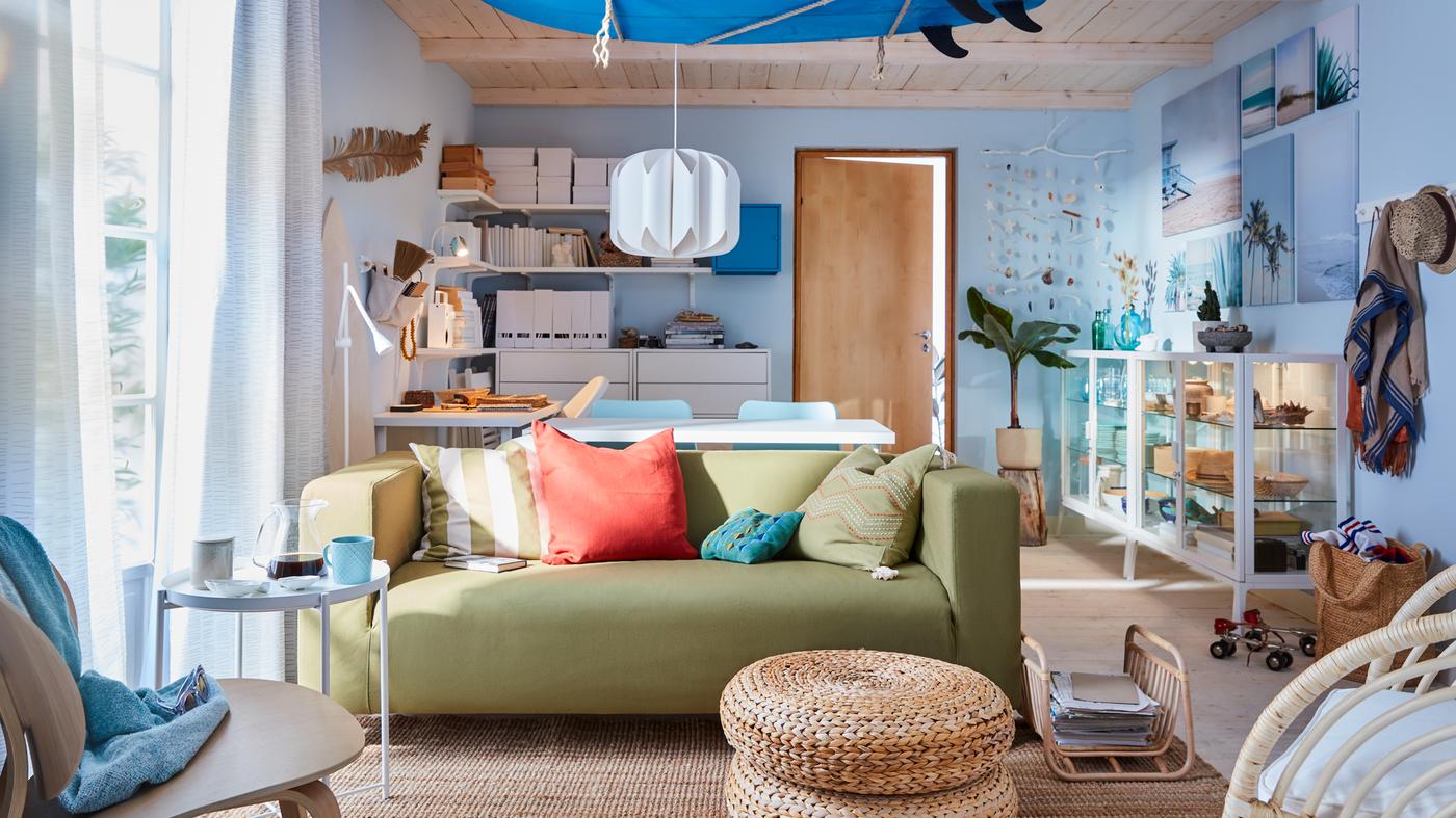 A surf-inspired living room with a yellow-green sofa, blue surfboard on the ceiling, white shelves, and blue walls.