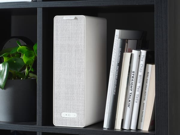 A SYMFONISK bookshelf speaker in a bookshelf, together with some books.