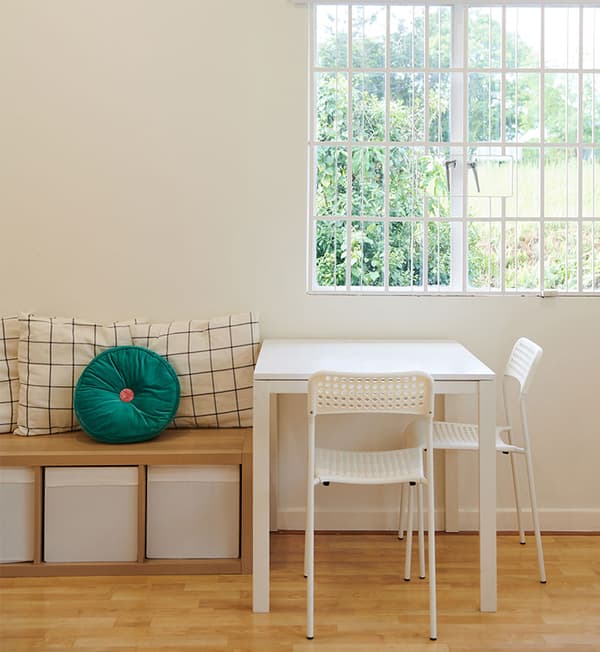 A table and chairs placed beside a bench with additional storage. 