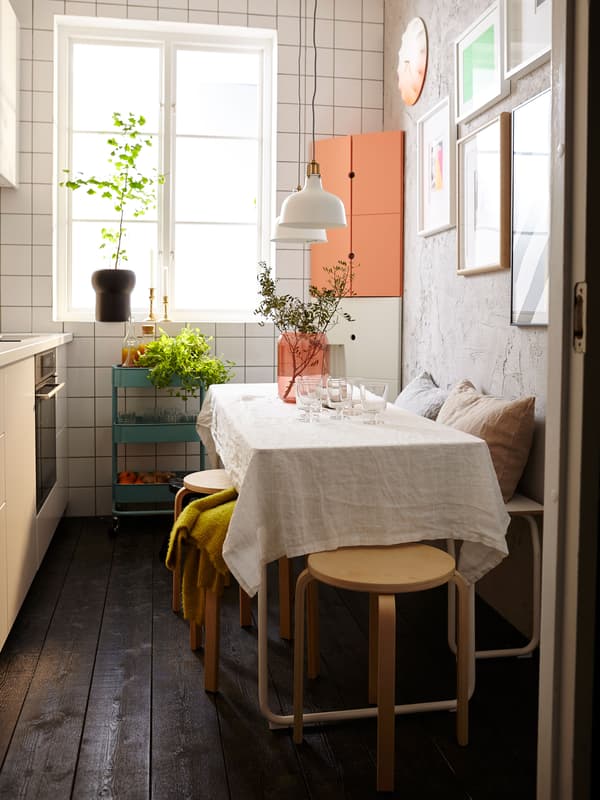A table in a small kitchen with stools and a bench for flexible seating.