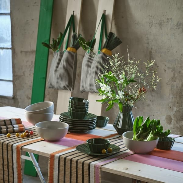 A table styled with potted plants and gardening tools, arranged against a window wall.