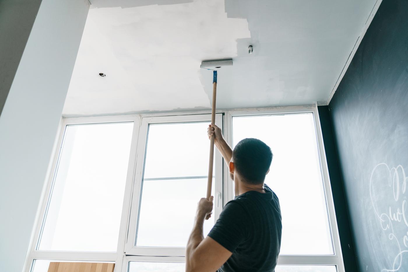A Task rabbit tasker painting a ceiling with a roller.