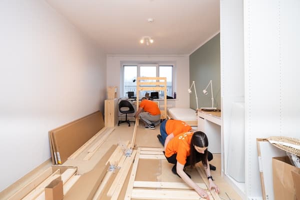 A team of IKEA volunteers assembles furniture and sets up the room.