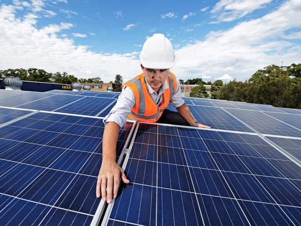 A tech installing solar panels onto a roof
