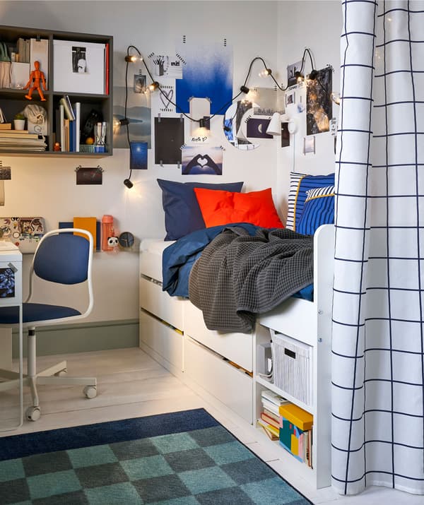 A teenager's bedroom with a single bed and under-bed storage, wall-mounted storage and a privacy curtain.