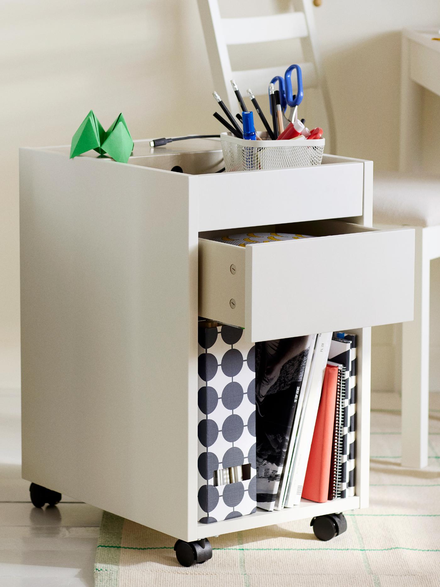 A TONSTAD drawer unit on castors in white with diverse items on and in it, in front of a TONSTAD extendable table and chair.