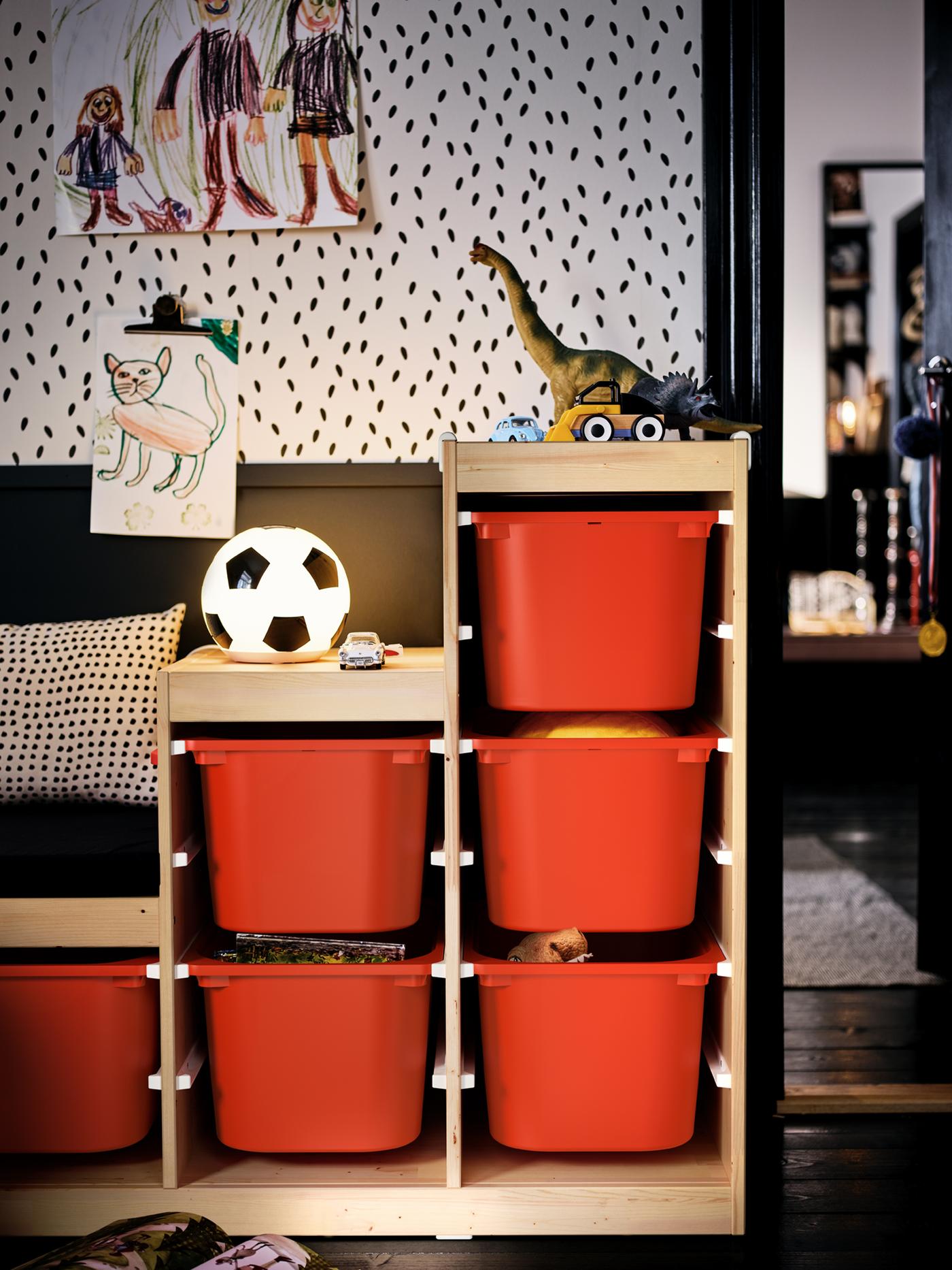 A toy-filled TROFAST unit with orange storage boxes in a kids’ room set in an otherwise black-and-white colour scheme.