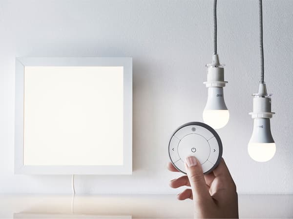 A TRÅDFRI smart remote control with a lighting panel and two lightbulbs.