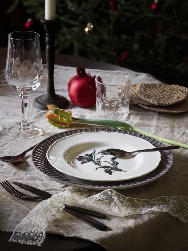 A traditional-looking table setting, with a white UPPLAGA plate at the centre layered on top of a blue plate.
