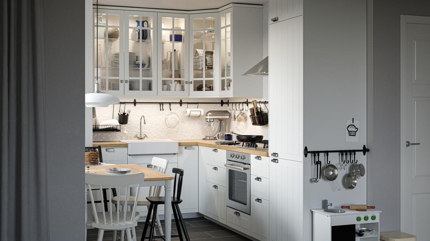A traditional-style kitchen with white fronts and cabinets with glass doors, a dining table, chairs and a play kitchen.