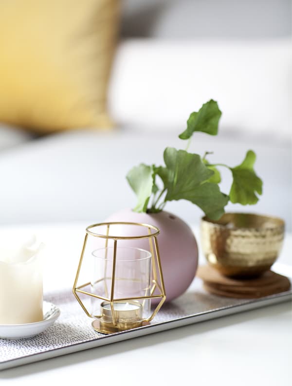A tray with candleholders, vases and plant cuttings.