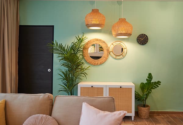 A turqoise room setting featuring a white chest of drawer and mirrors hung on the wall.