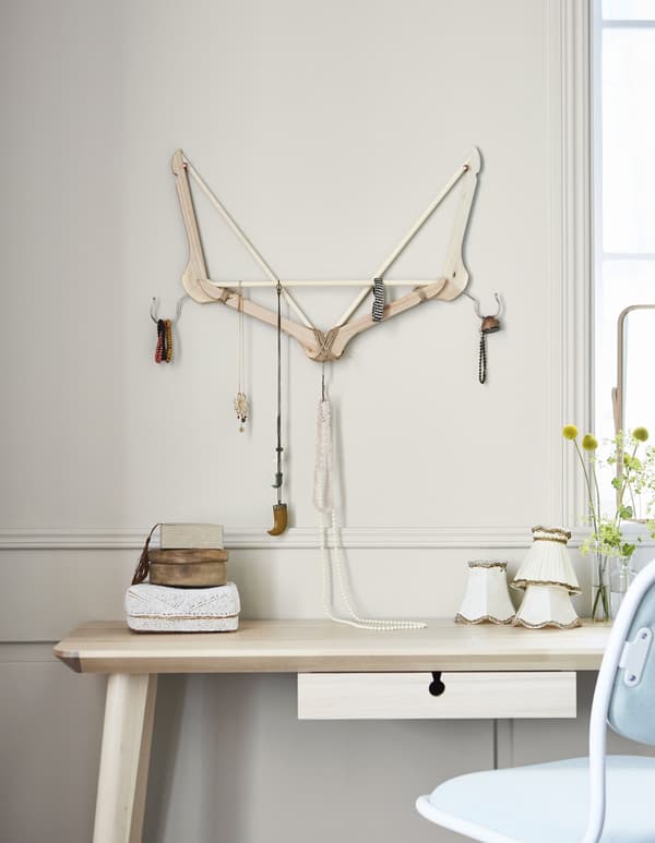 A unique jewellery display and hanger made from BUMERANG wooden hangers is mounted on the wall above a desk.
