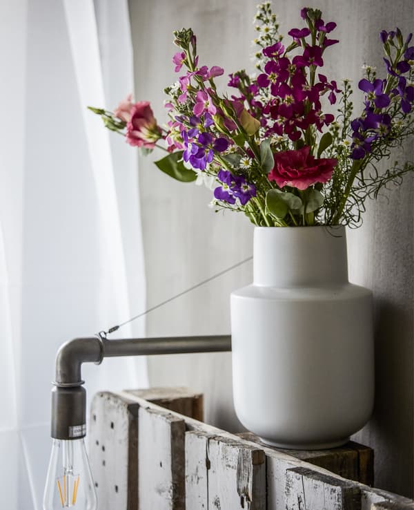 A vase of colourful flowers on a bedhead.