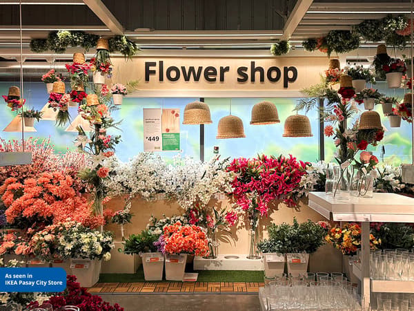 A vibrant flower shop display featuring a variety of colorful artificial flowers, hanging decorations, and glass vases.