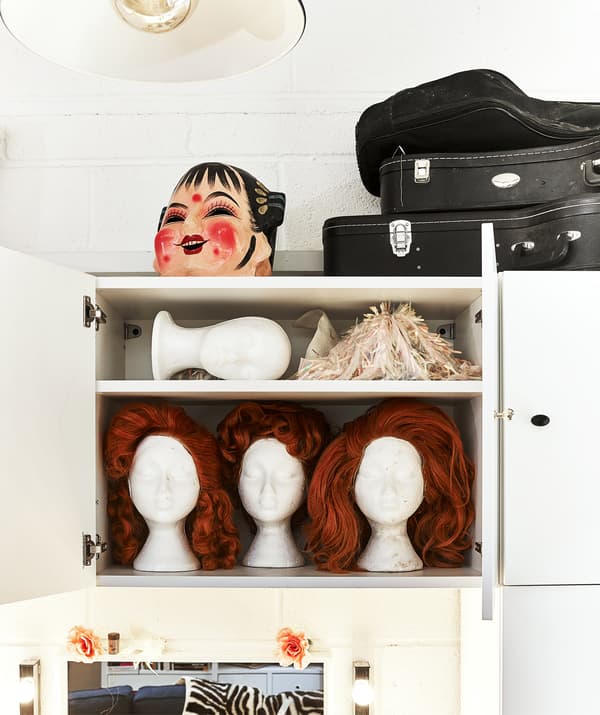A wall-mounted cupboard containing several ginger wigs on stands.