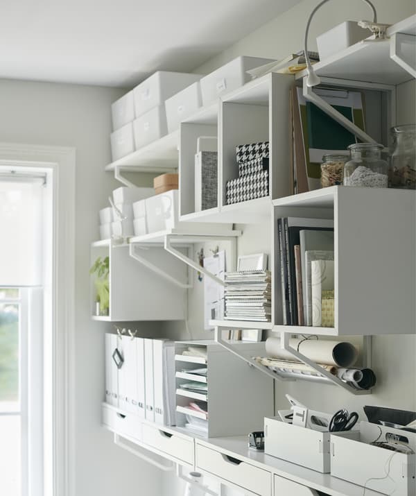 A wall of storage shelves, boxes and trays filled with office items.