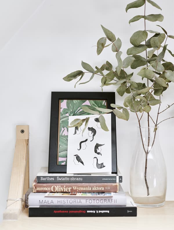 A wall shelf display with books, pictures and vase.