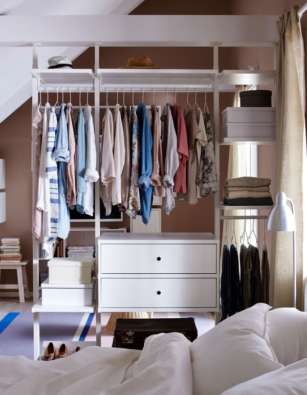 A wardrobe dividing two rooms, featuring clothes hanging and folded.
