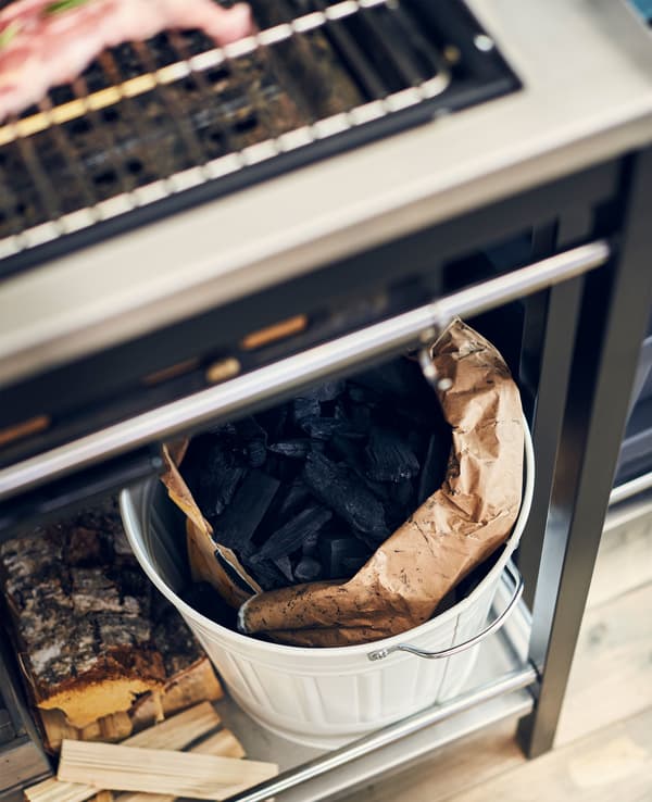 A waste bin with a bag of charcoal inside.