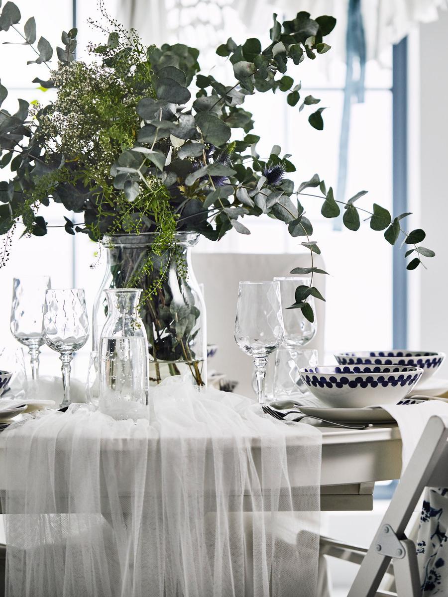 A wedding table with a floral centrepiece, blue fabric backed TERJE chairs with a white traditional dining set.