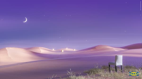 A white and blue-striped BERGMUND chair, with black legs, stands on a grassy ridge above a violet-coloured desert landscape.