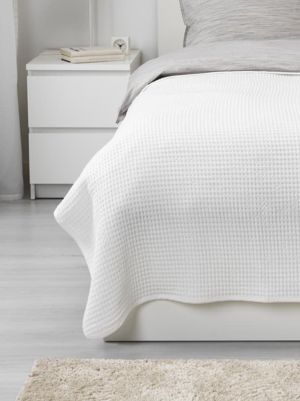 a white bedspread on top of a bed