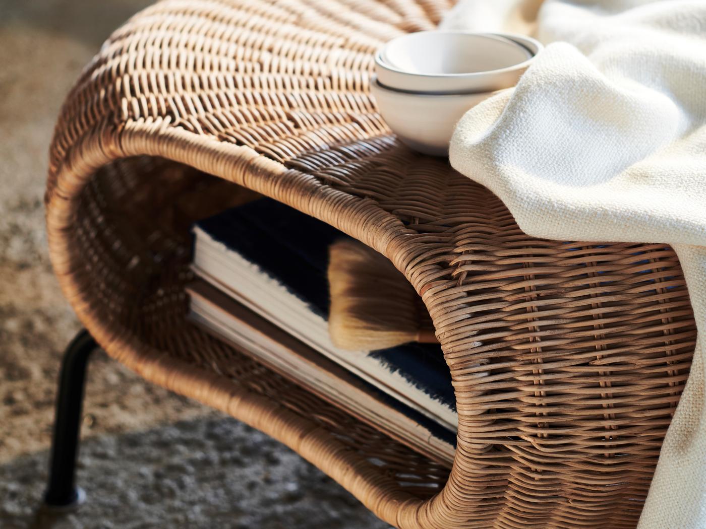 A white blanket and three white bowls on a GAMLEHULT footstool with books stored inside.