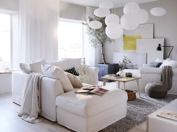 A white corner sofa with footstool with coffee table and chaise longue.