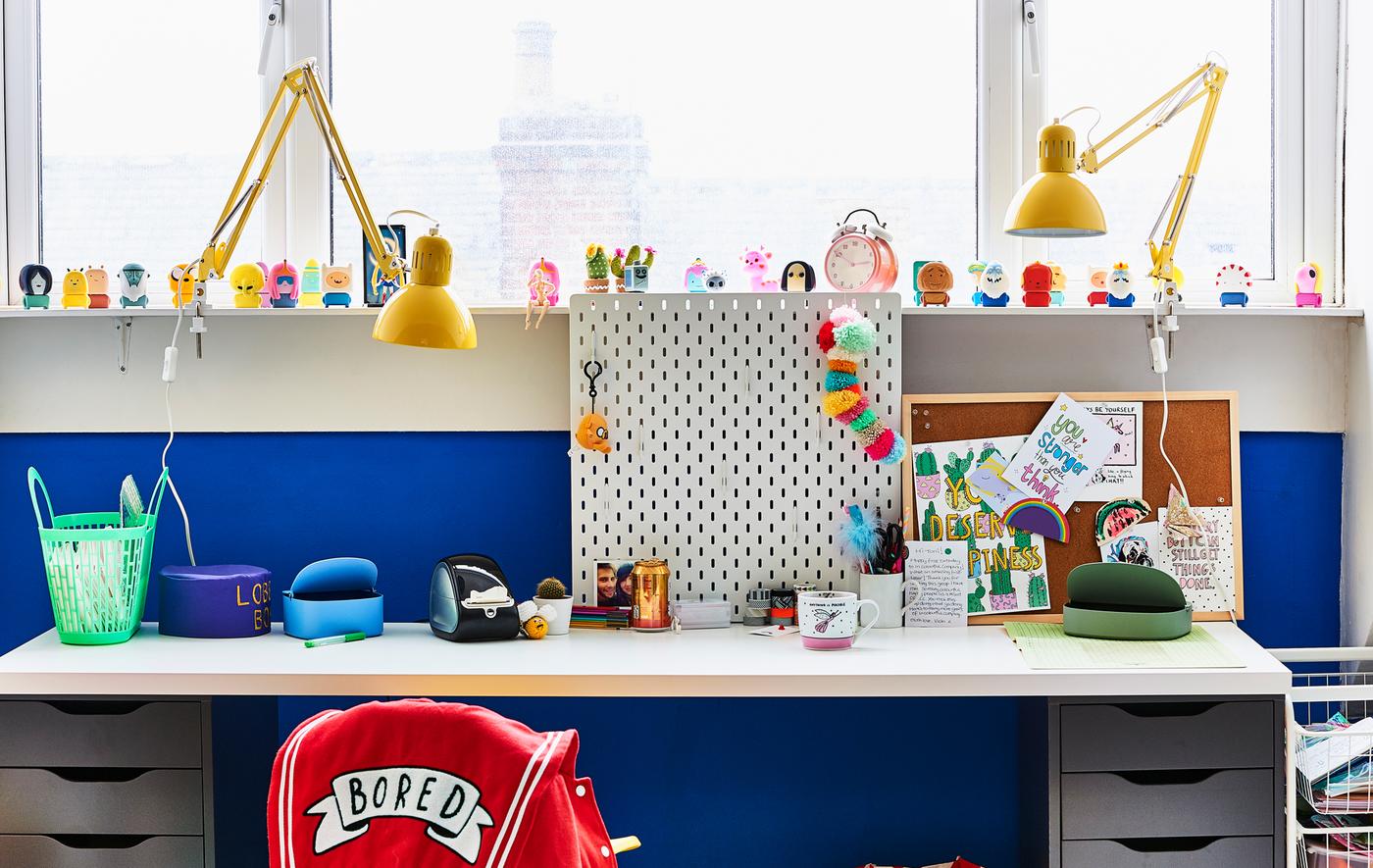 A white desk and yellow lamps against a blue wall.