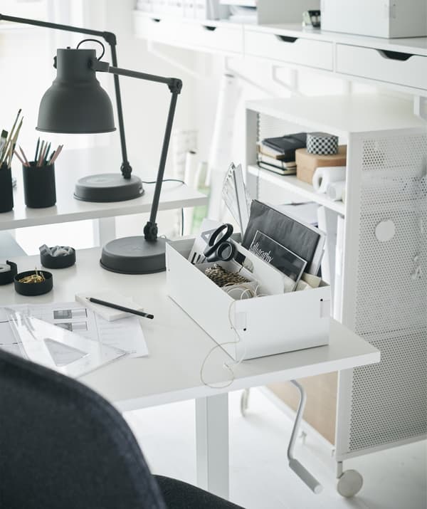 A white desk with a desk tidy and a dark grey desk lamp.
