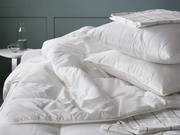 A white duvet inset sitting on a bed with white pillows on top.
