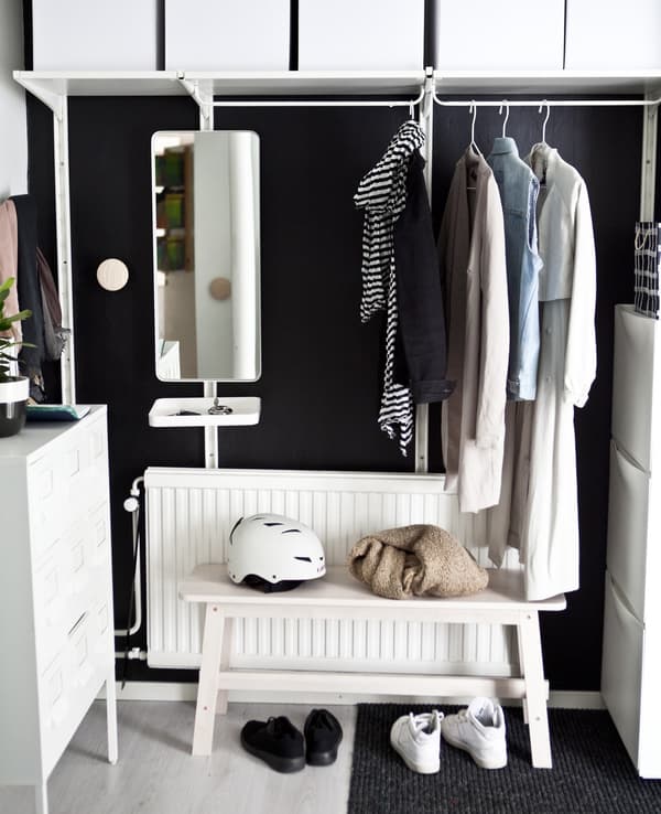 A white hanging rail with a white shelf and boxes above and a white bench below.