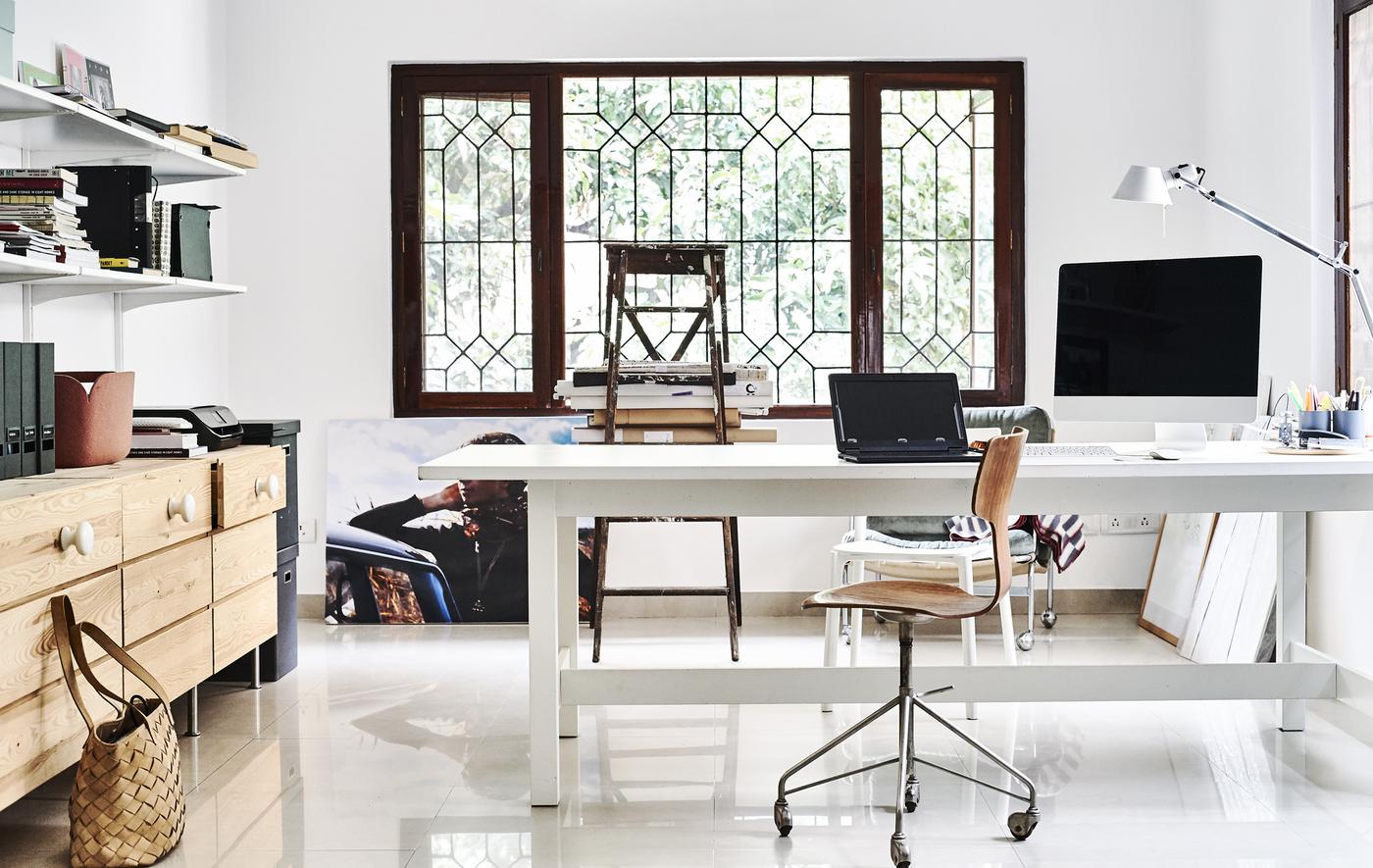 A white home office with wooden chest of drawers and shelving.