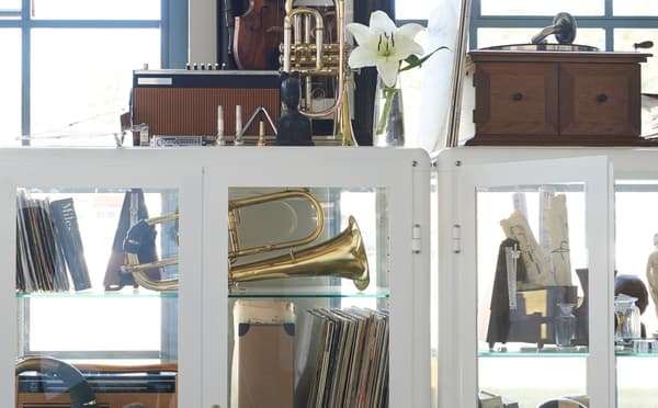 A white IKEA FABRIKÖR glass cabinet, displaying a collection of souvenirs.