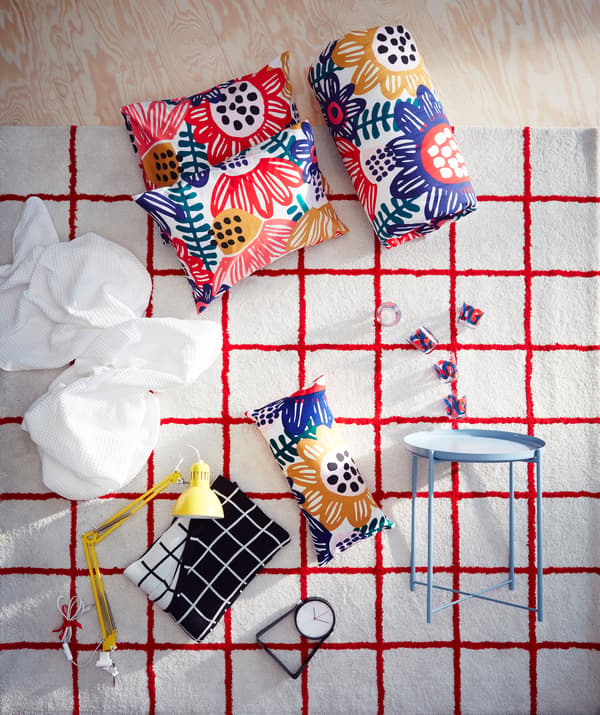 A white IKEA SIMESTED rug with a bright red square pattern and high pile is the backdrop for matching bedroom products.