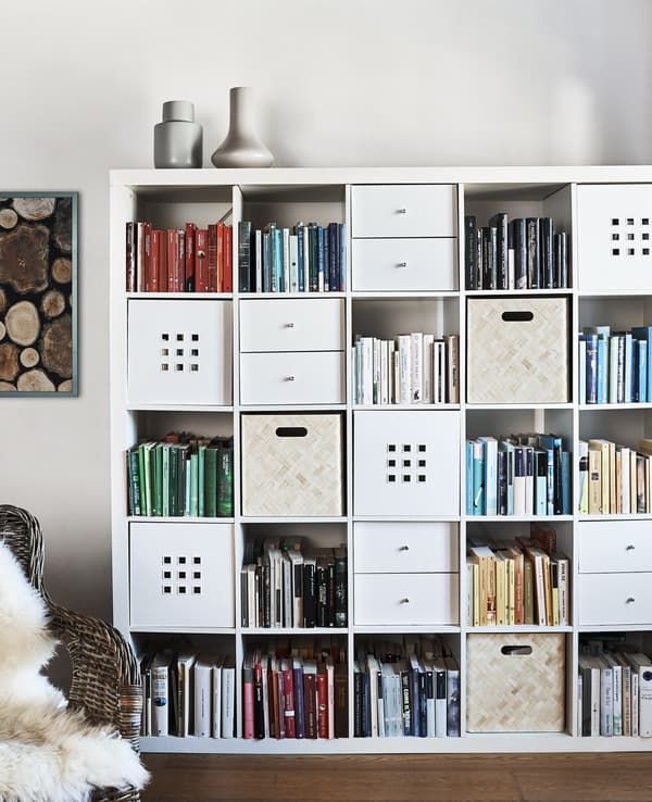 A white KALLAX unit with storage boxes in some alcoves.