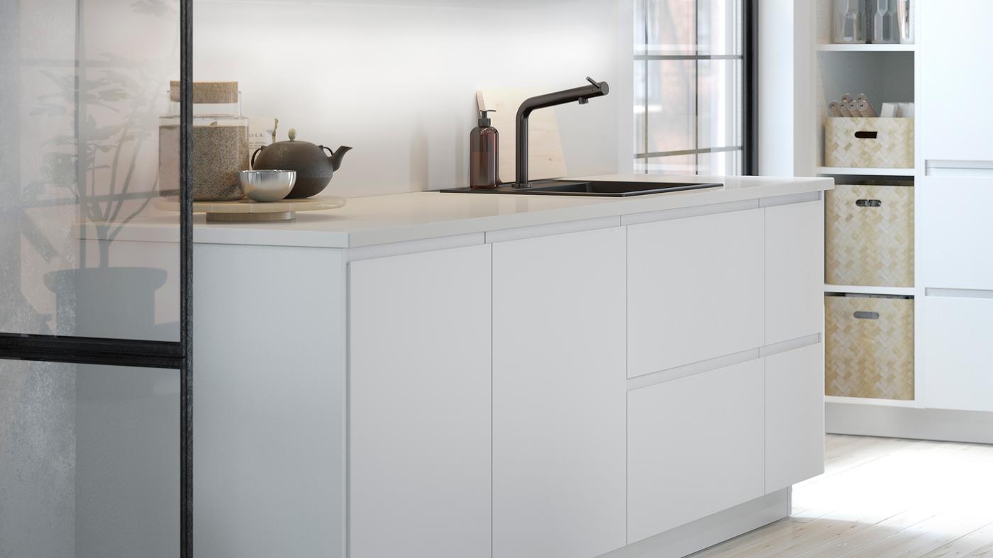 A white kitchen with matt white kitchen doors and drawer fronts, a white worktop and a mixer tap.