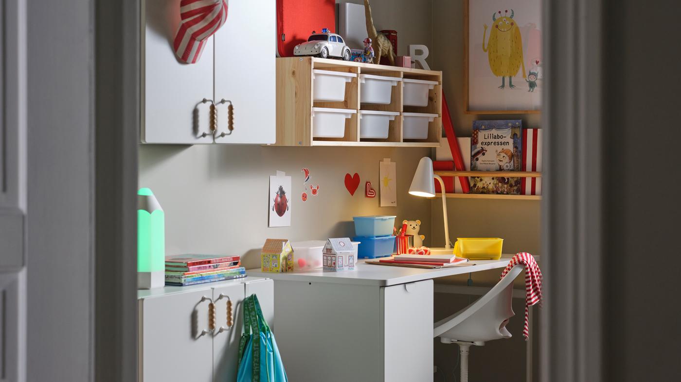 A white LÄRANDE desk with a pull-out storage unit, a white children’s desk chair and a pine/white wall storage combination.