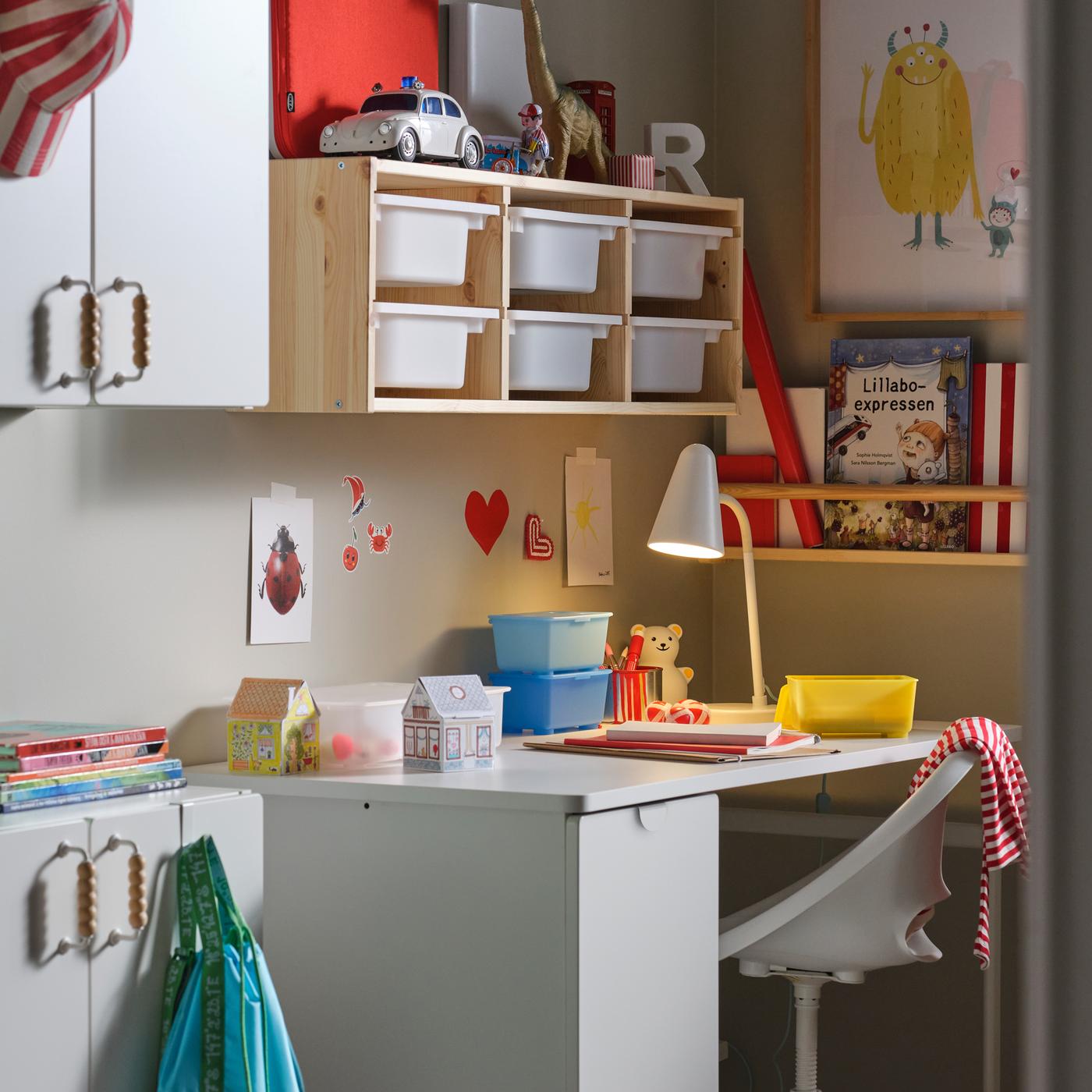 A white LÄRANDE desk with pull-out storage unit with a white children’s desk chair in front and a mix of wall storage above.