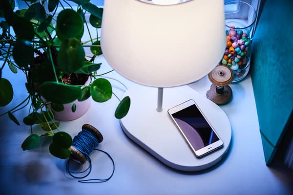 A white lamp with smart charging functionality charging a phone