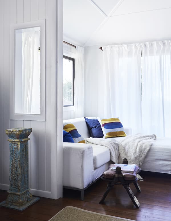 A white living room with brightly coloured cushions.