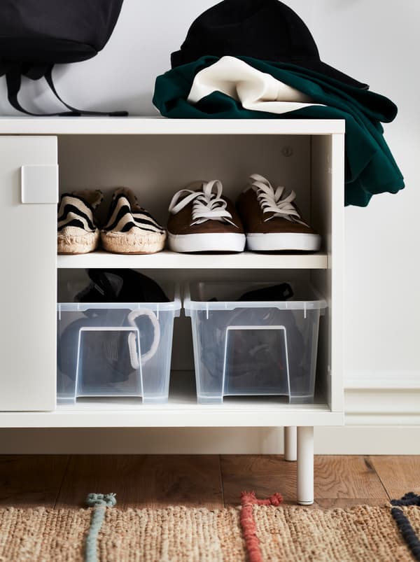 A white MACKAPÄR bench with storage compartments and SAMLA transparent plastic boxes inside for shoes and helmets.