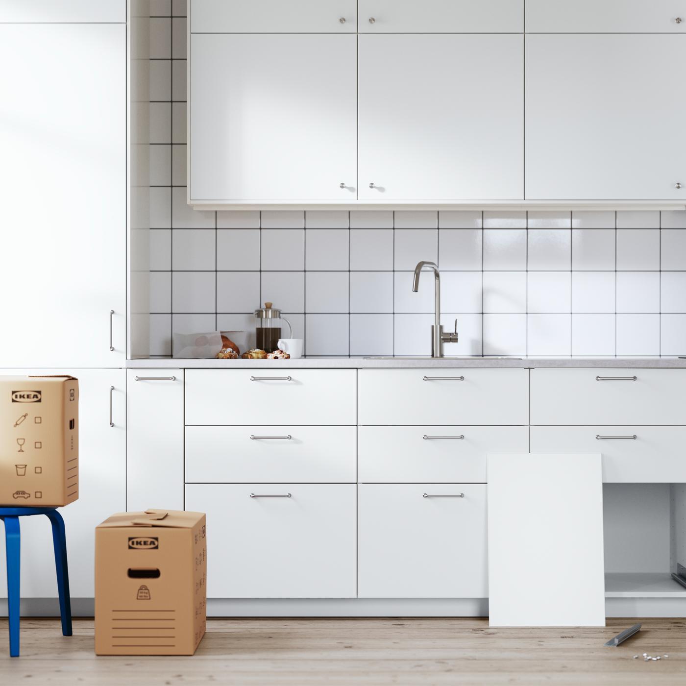 A white METOD kitchen in the last stages of installation. A drawer sits on the floor and its front leans against a cabinet.