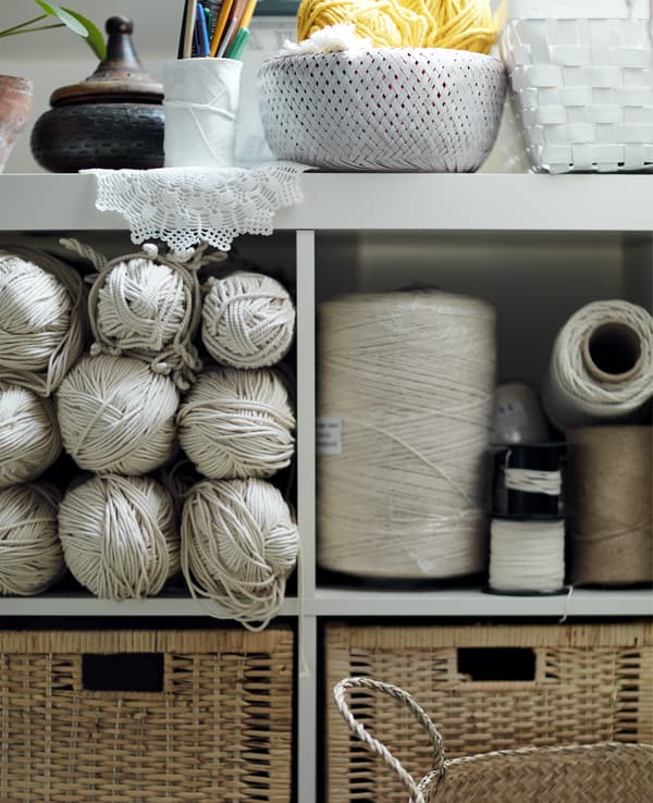 A white open shelving unit filled with craft supplies.